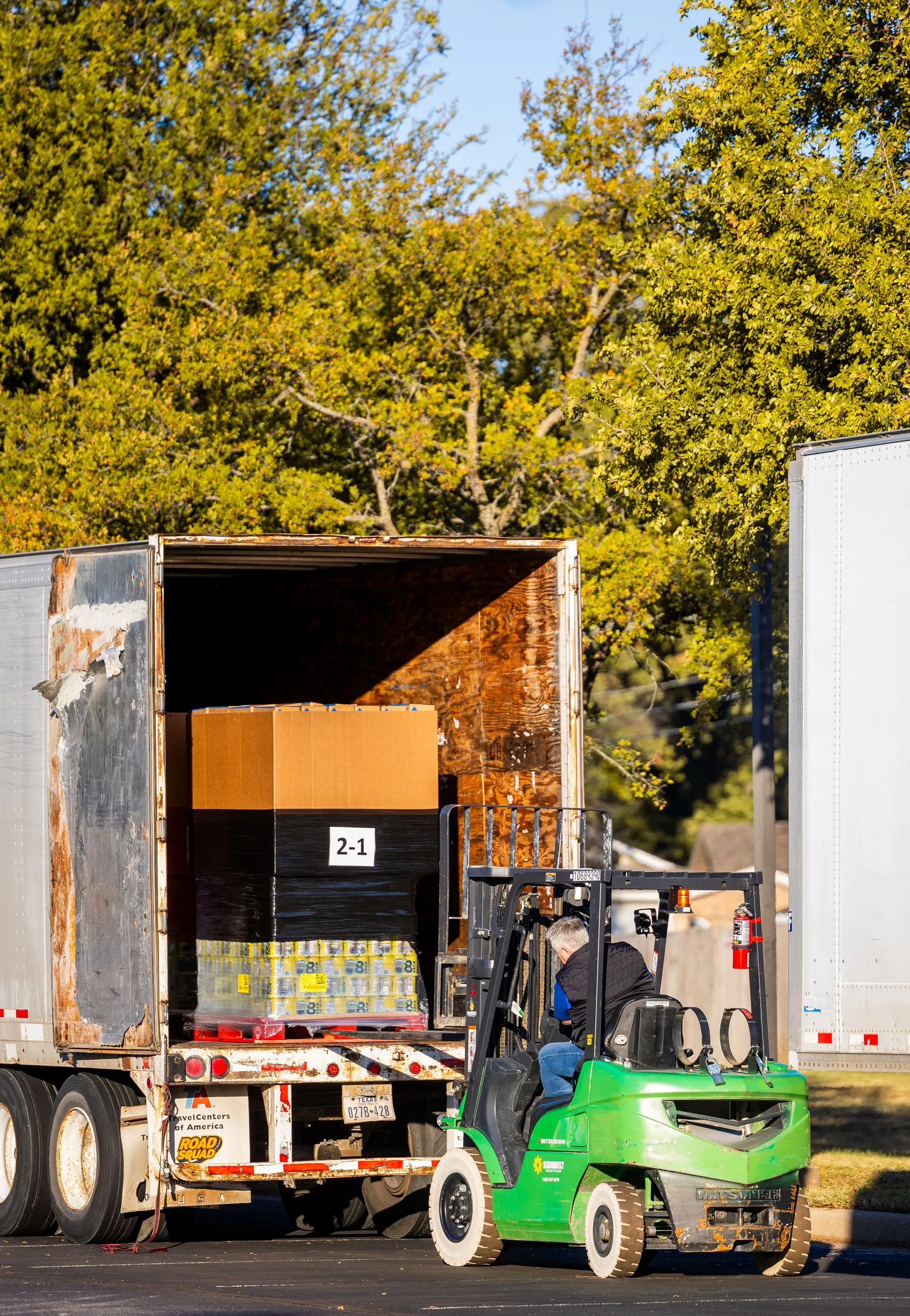 A pallet of containers being loaded onto a delivery vehicle