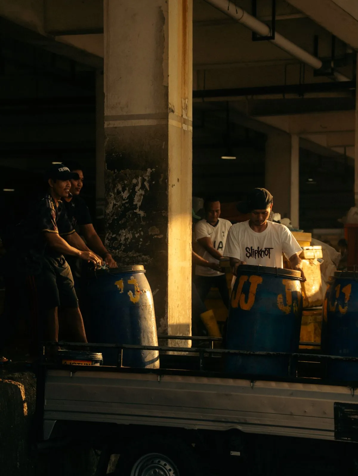 Workers loading industrial containers onto a vehicle